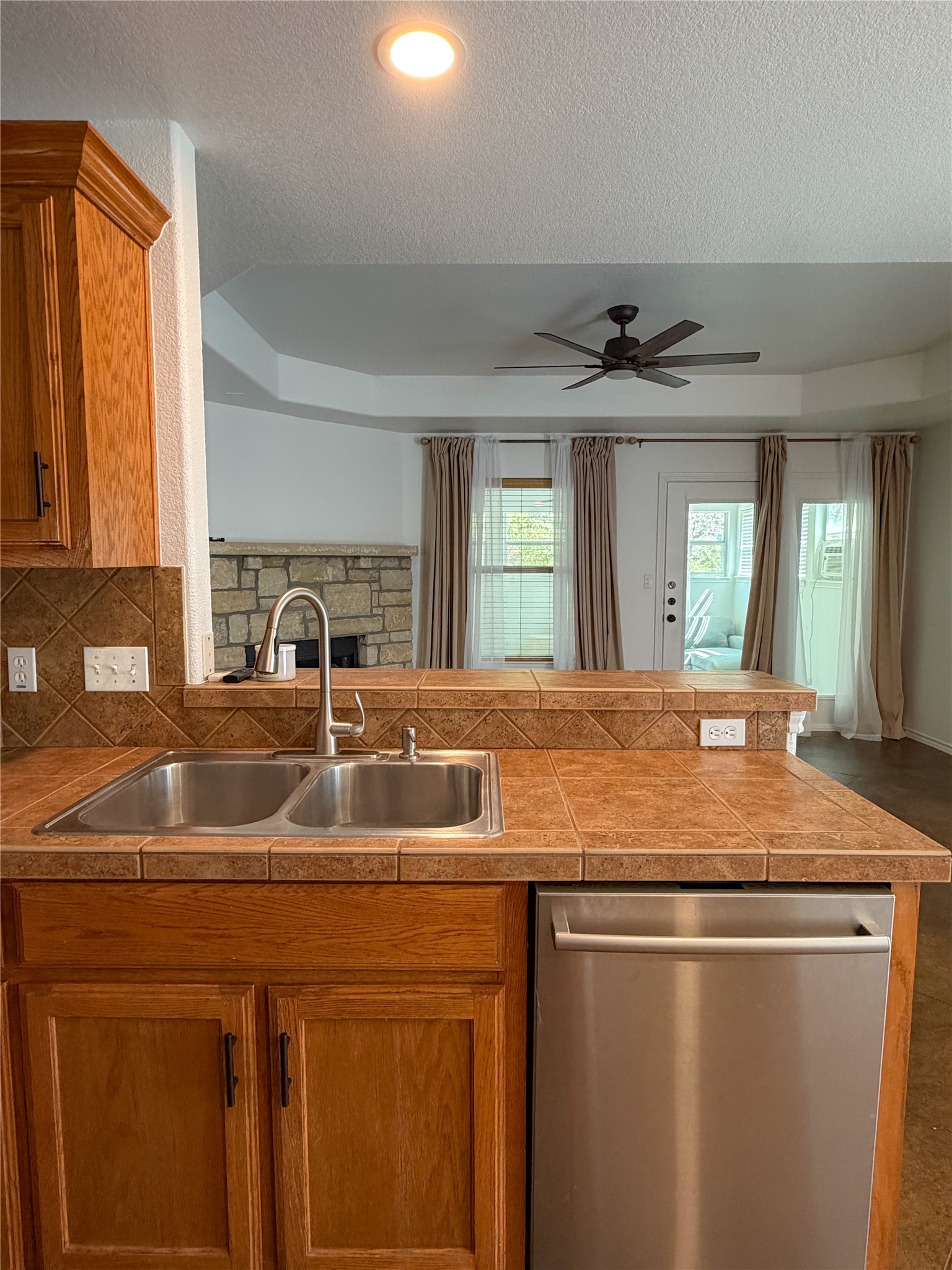430 Summit Ridge Drive North Point Venture, TX 78645 - Photo 15 of 39 Kitchen featuring dishwasher, ceiling fan, wood finish cabinetry, tile countertops, and a textured ceiling
