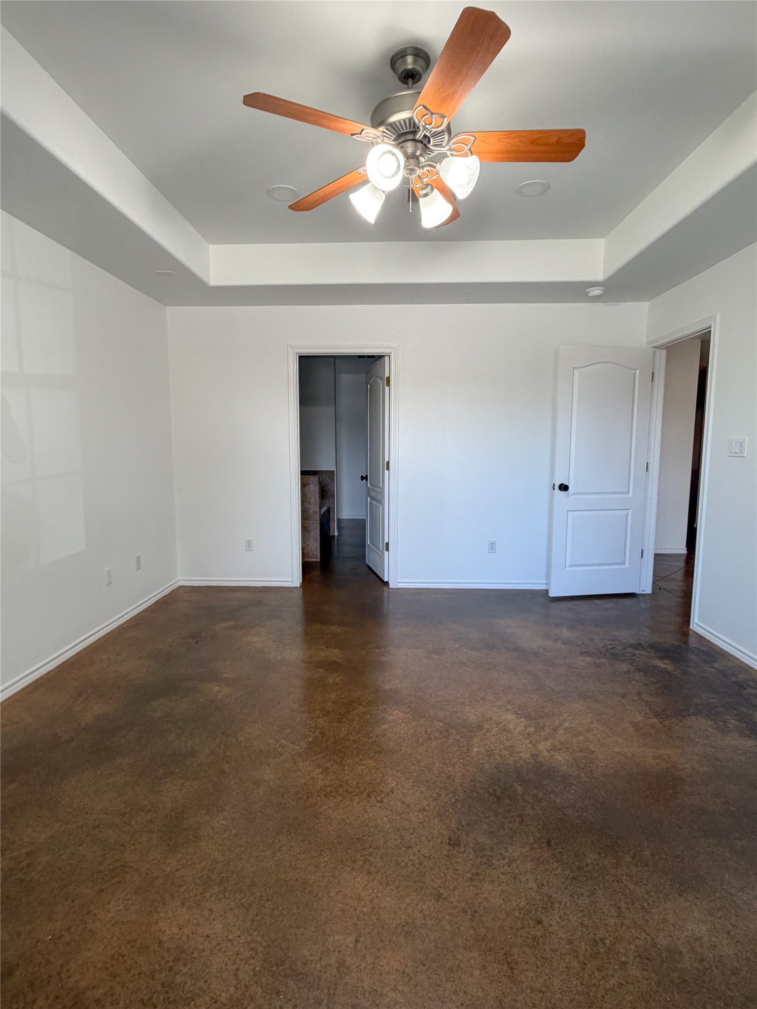 430 Summit Ridge Drive North Point Venture, TX 78645 - Photo 5 of 39 Unfurnished bedroom featuring a tray ceiling, concrete floors, a spacious closet, and ceiling fan
