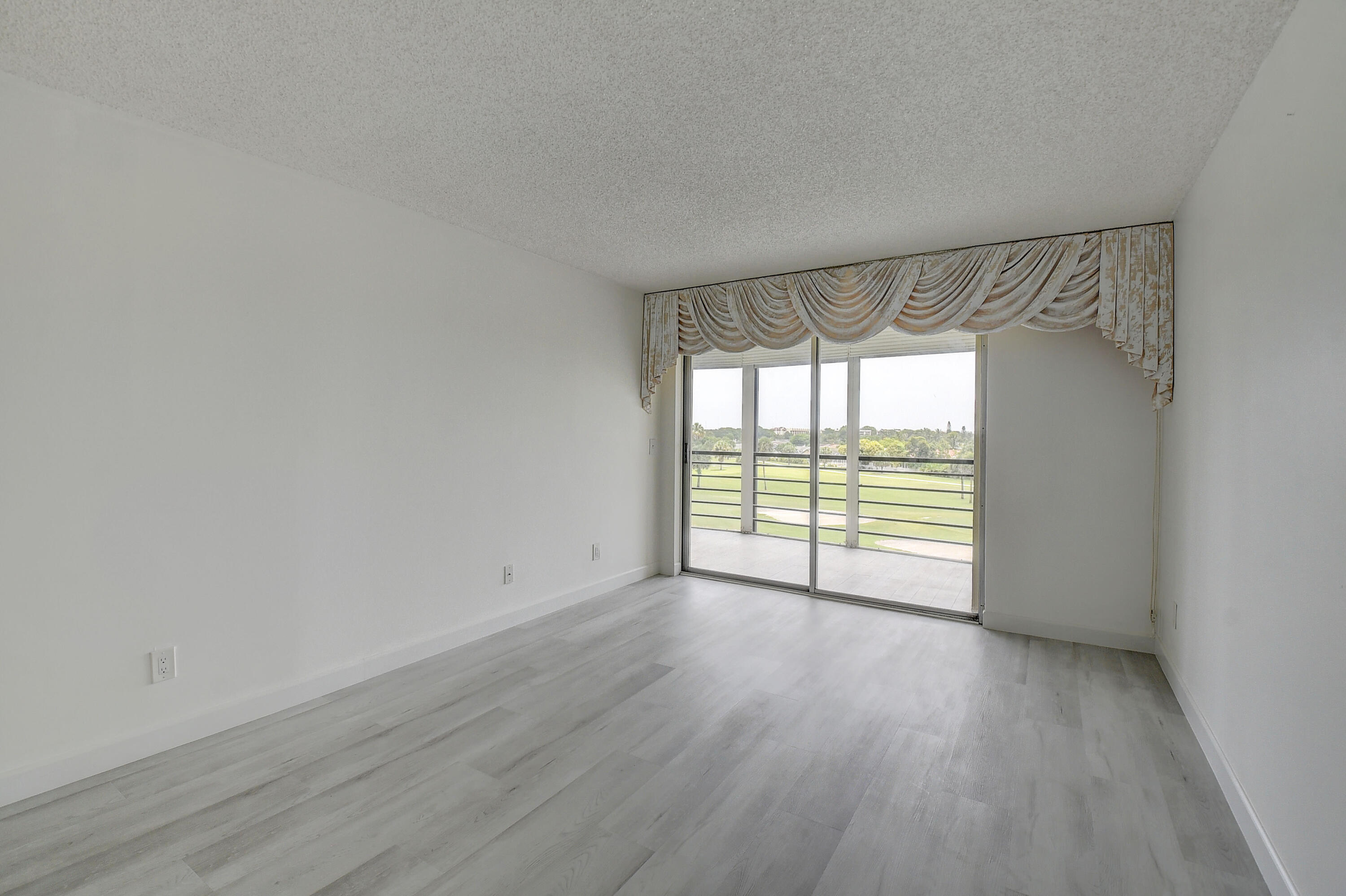 23305 Barwood Lane North, Unit 406 Boca Raton, FL 33428 - Photo 16 of 41 a view of an empty room with wooden floor and a window