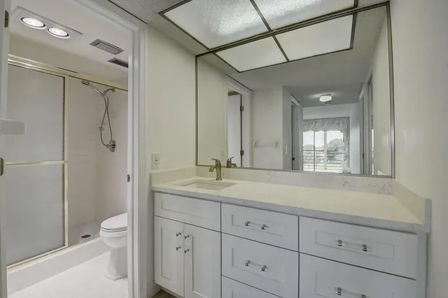 a bathroom with a granite countertop sink a toilet and shower