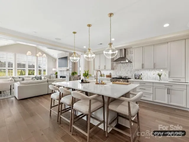 a kitchen with stainless steel appliances kitchen island granite countertop a dining table chairs and white cabinets