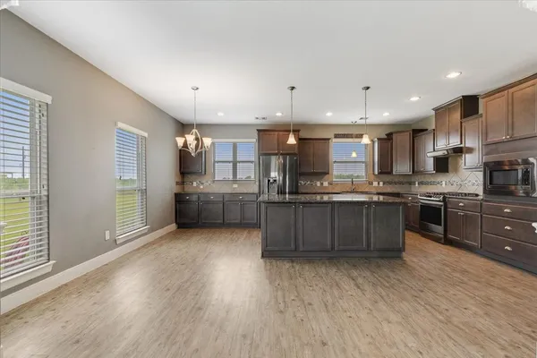 a kitchen with stainless steel appliances kitchen island granite countertop a large counter top and a stove