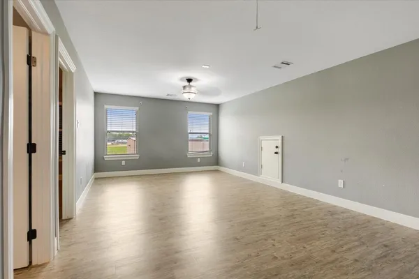 a view of an empty room with window and wooden floor