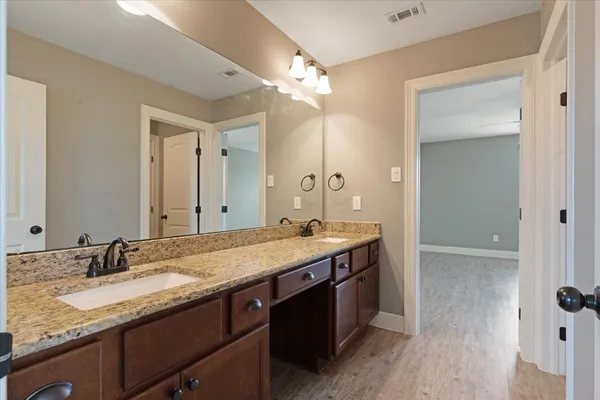 a bathroom with a granite countertop sink double vanity and a mirror