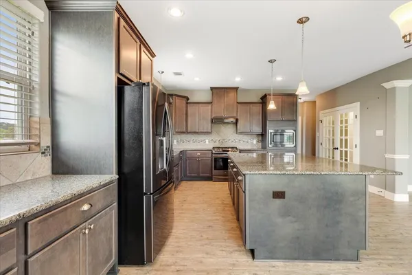 a kitchen with kitchen island a counter top space a sink stainless steel appliances and cabinets