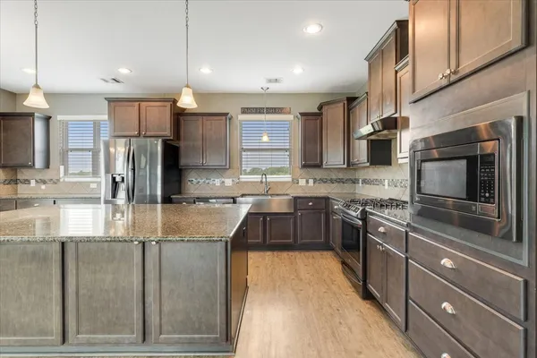 a kitchen with stainless steel appliances granite countertop a sink stove and refrigerator