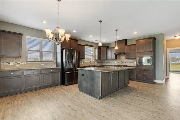 a large kitchen with a large island in the center and stainless steel appliances