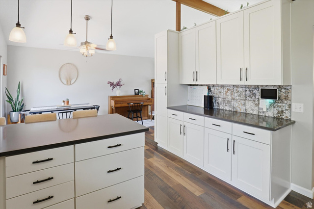 8938 Manchester Lane Sandy, UT 84093 - Photo 13 of 50 Kitchen featuring white shaker cabinetry, dark countertops, and a distressed metallic tile backsplash