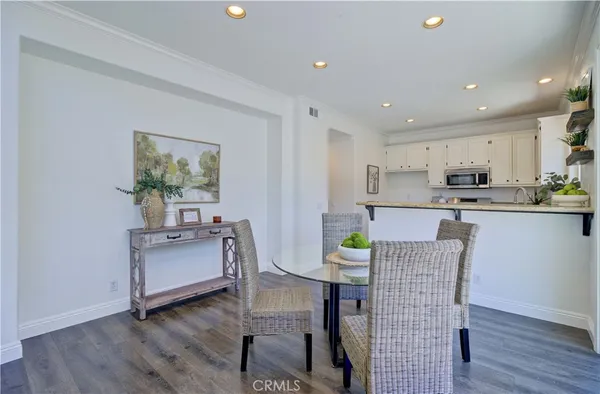 a kitchen with stainless steel appliances kitchen island granite countertop a dining table chairs microwave and sink