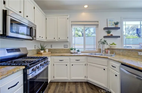 a kitchen with granite countertop a sink a stove and cabinets