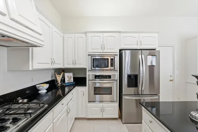 a kitchen with stainless steel appliances granite countertop a stove a refrigerator a dining table and chairs