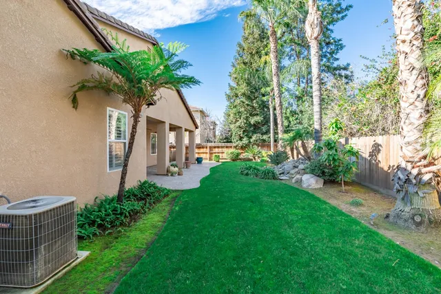 a view of a white house with a big yard and potted plants