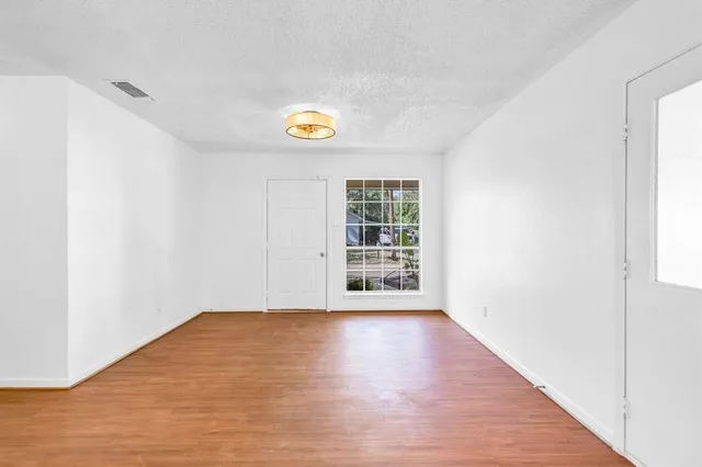 a view of an empty room with a window and wooden floor