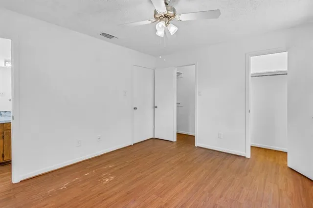 an empty room with wooden floor closet and windows