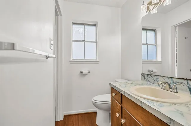 a bathroom with a granite countertop sink toilet and a mirror