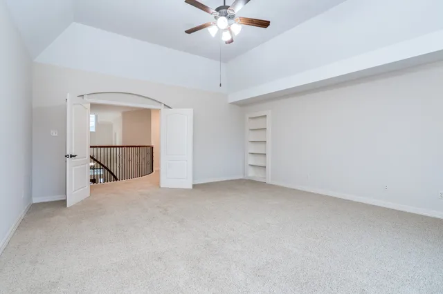 an empty room with chandelier fan and windows