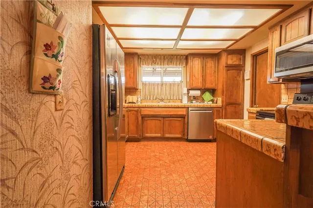 a kitchen with stainless steel appliances a refrigerator a sink and wooden cabinets