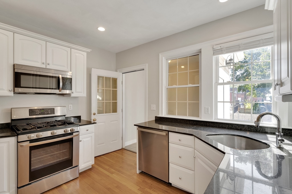 66 Webster Street, Unit 66 Newton, MA 02465 - Photo 11 of 40 a kitchen with granite countertop a sink stainless steel appliances and white cabinets