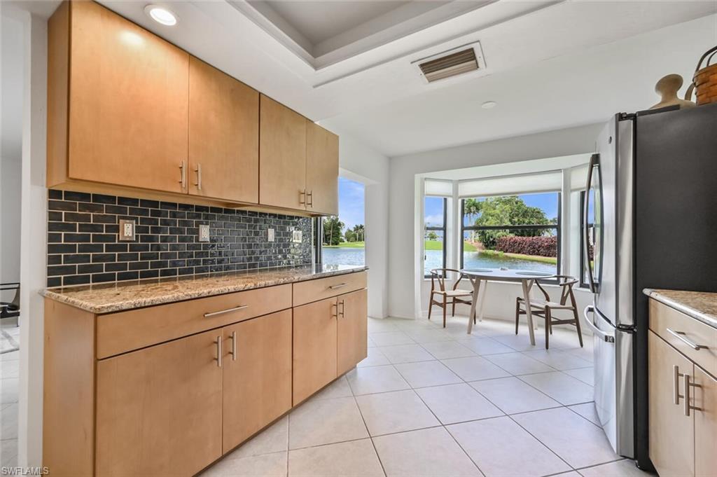 492 Veranda Way, Unit E105 Naples, FL 34104 - Photo 11 of 34 a kitchen with granite countertop white cabinets and refrigerator