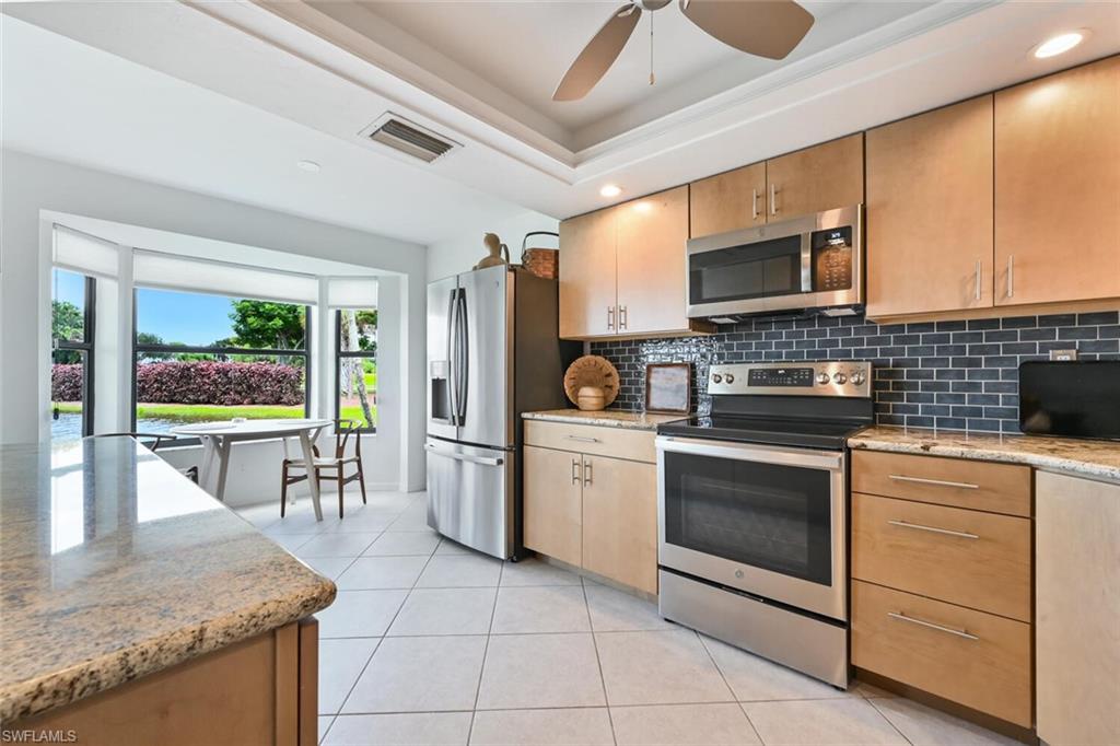 492 Veranda Way, Unit E105 Naples, FL 34104 - Photo 10 of 34 a kitchen with stainless steel appliances granite countertop a stove a sink and a microwave