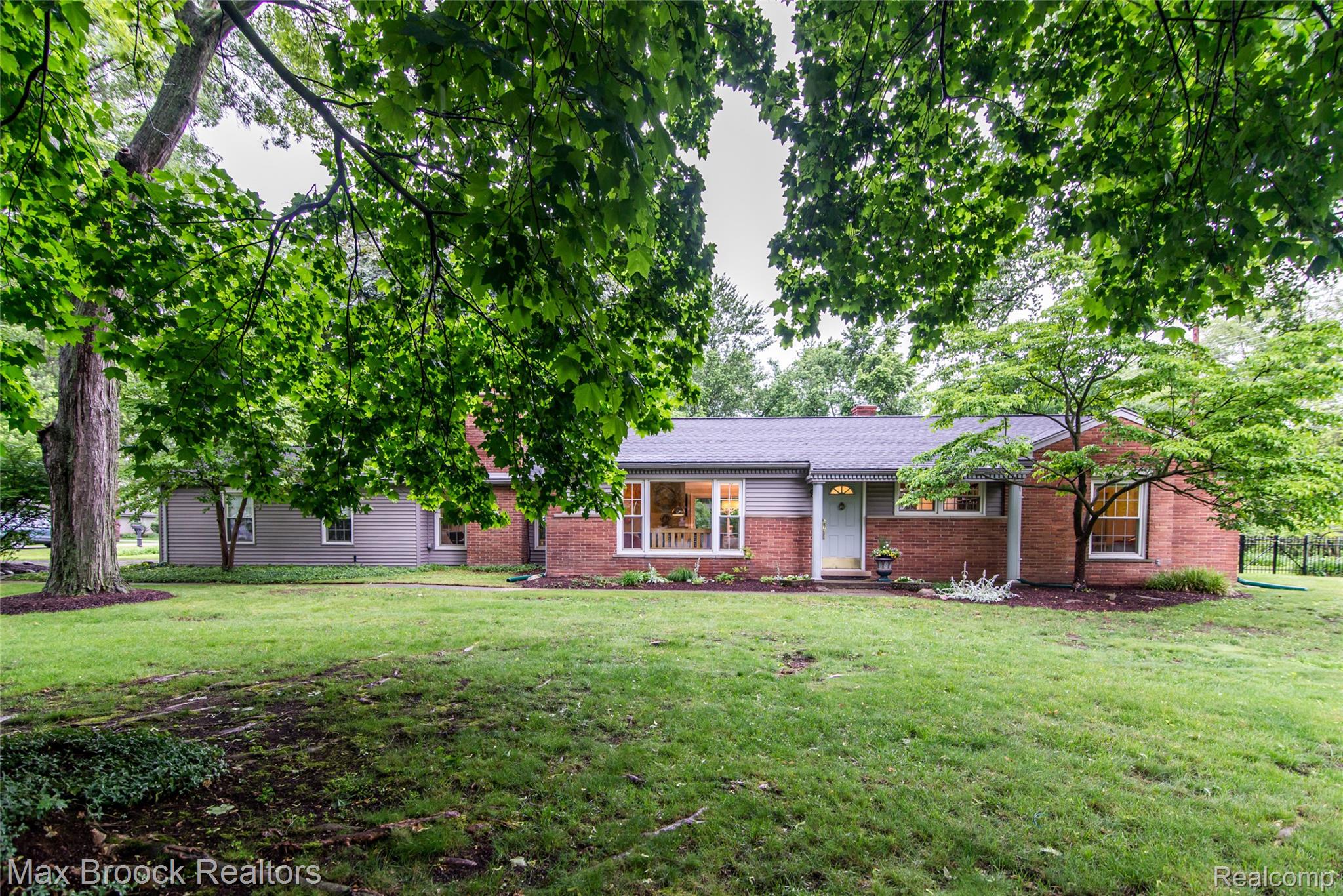 6799 East Dartmoor Road West Bloomfield, MI 48322 - Photo 36 of 36 Brick and siding exterior featuring a light blue entry door, an expansive front lawn, mature trees, and established landscaping