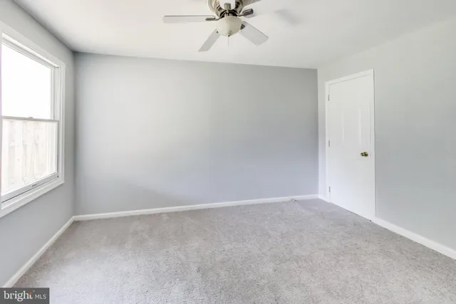an empty room with a window and a fan