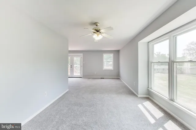 an empty room with chandelier fan and windows