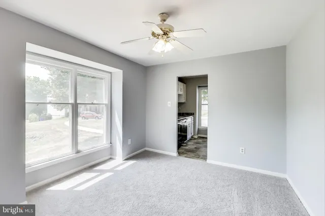 an empty room with chandelier fan and windows