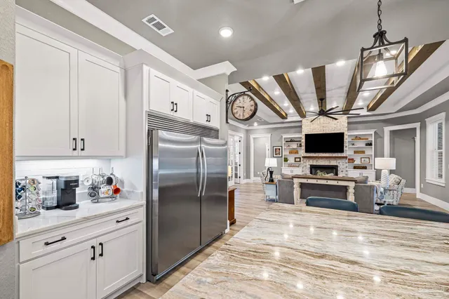 a kitchen with stainless steel appliances granite countertop a sink dishwasher and a refrigerator with wooden floor