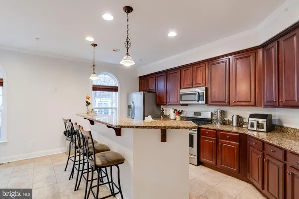 a kitchen with stainless steel appliances granite countertop a stove a sink dishwasher and a refrigerator with wooden floor