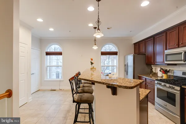 a kitchen with stainless steel appliances kitchen island granite countertop a table chairs sink and cabinets