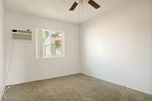 an empty room with ceiling fan and windows