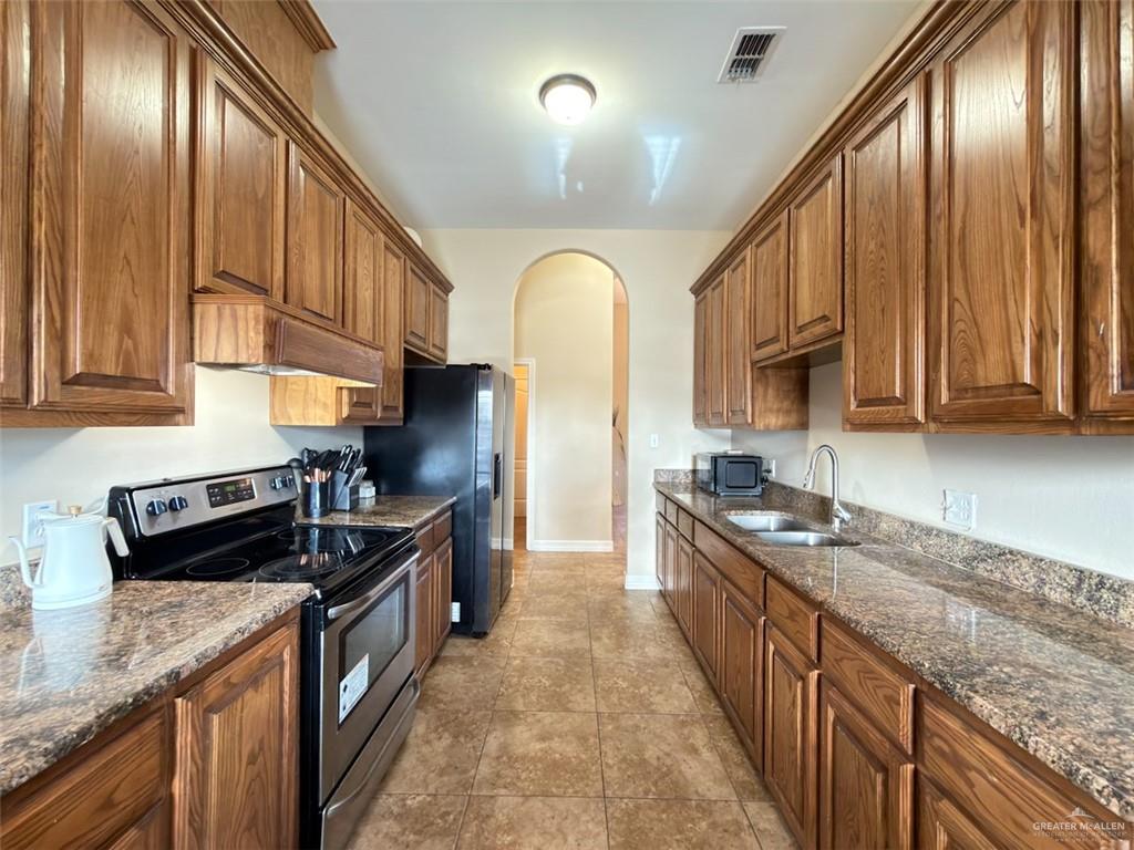208 North 15th Street Hidalgo, TX 78557 - Photo 22 of 26 a kitchen with granite countertop stainless steel appliances a sink stove top oven and cabinets