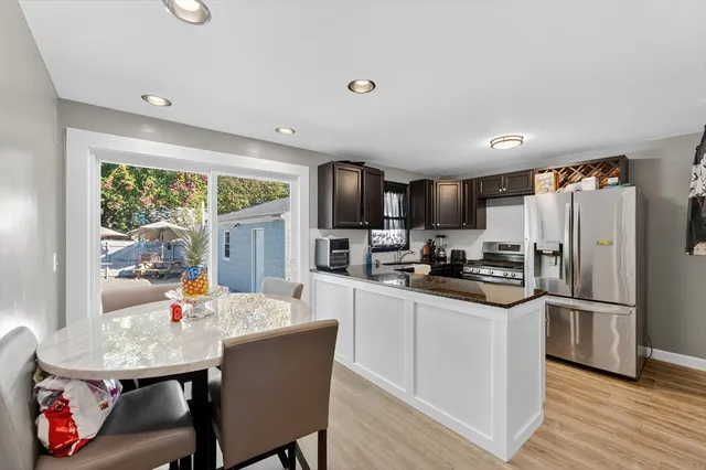 a kitchen with stainless steel appliances a dining table chairs refrigerator and sink