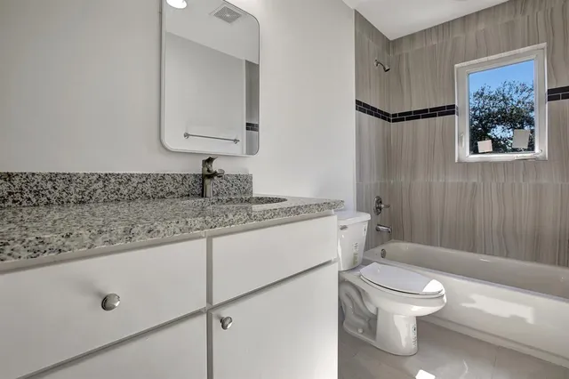 a bathroom with a granite countertop sink mirror vanity and toilet