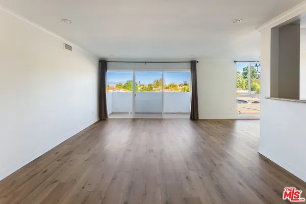 a view of an empty room with a window and wooden floor