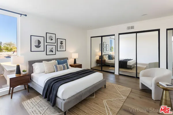 a spacious bedroom with a bed a couch and a large window