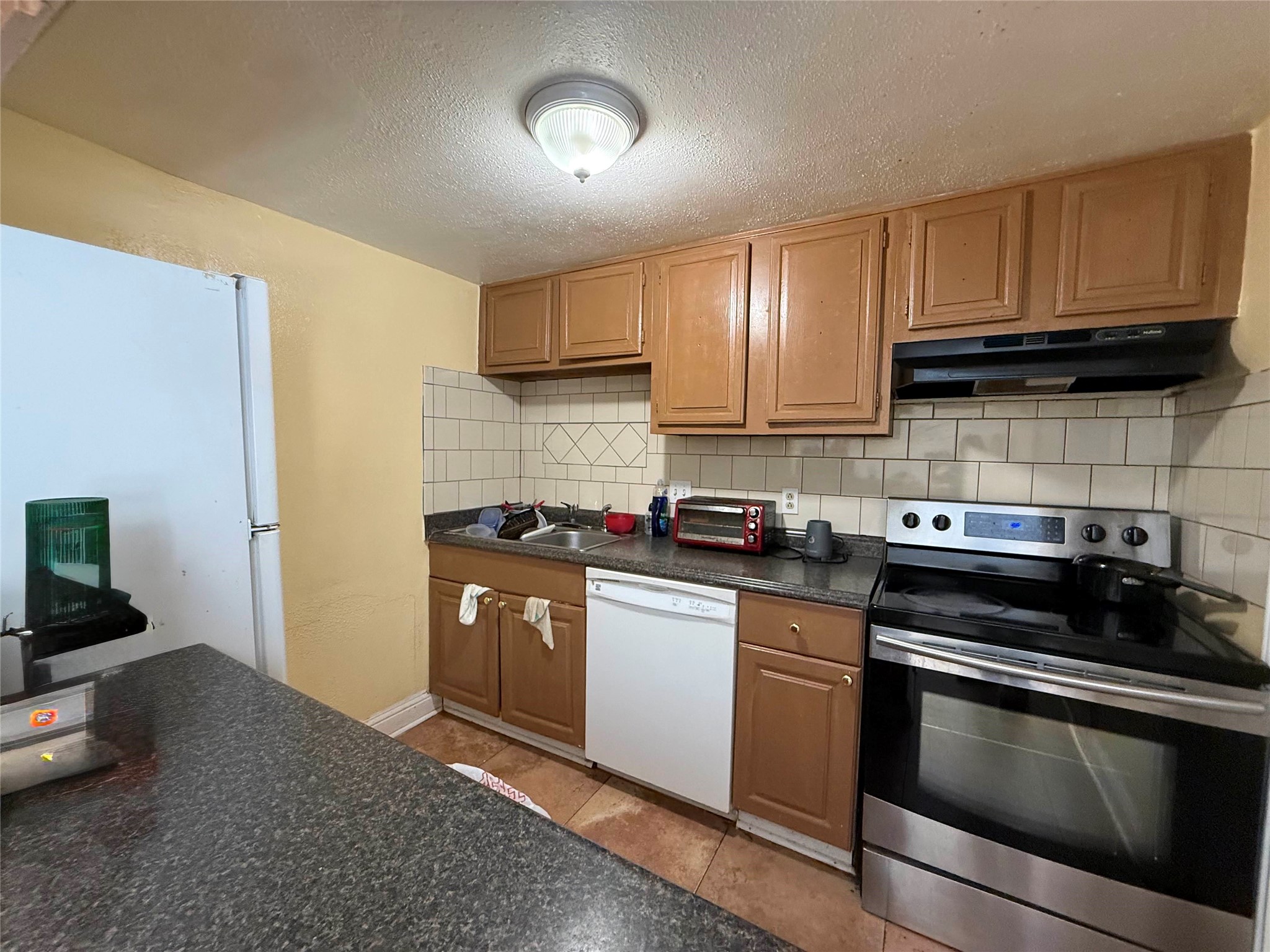 7047 Bissonnet Street, Unit 32 Houston, TX 77074 - Photo 4 of 19 a kitchen with stainless steel appliances granite countertop a stove a sink and a refrigerator