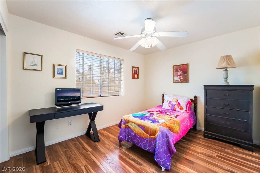 3631 South Blagg Road Pahrump, NV 89048 - Photo 27 of 47 A comfortable bedroom features warm-toned wood flooring and a refreshing ceiling fan.