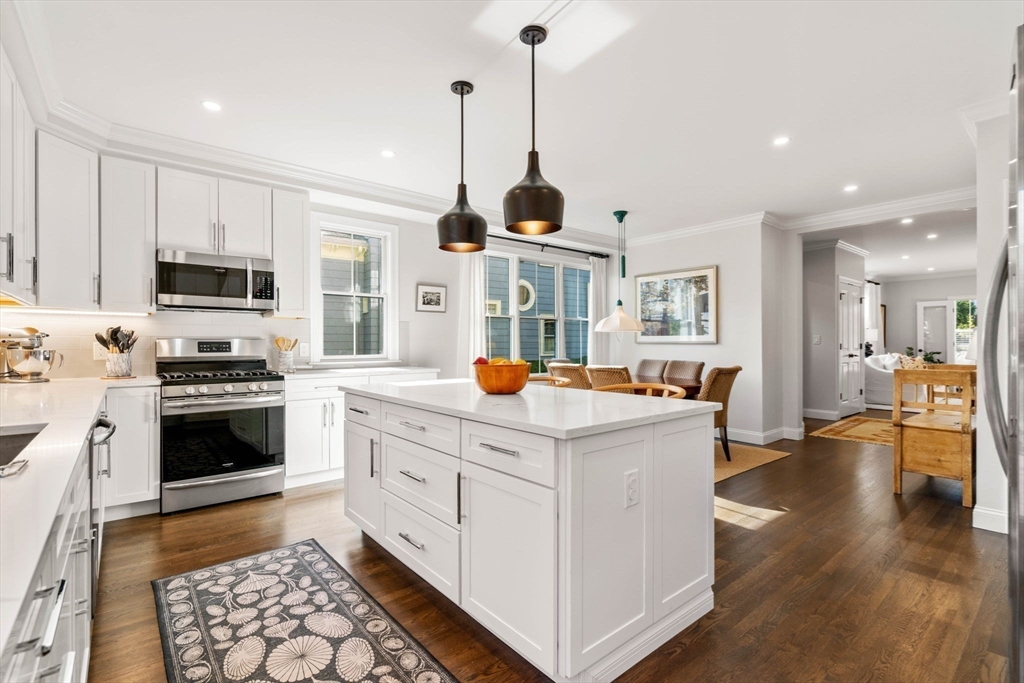 35 Algonquin Road, Unit 35 Chestnut Hill, MA 02467 - Photo 7 of 38 a kitchen with kitchen island a stove a sink a dining table and chairs with wooden floor