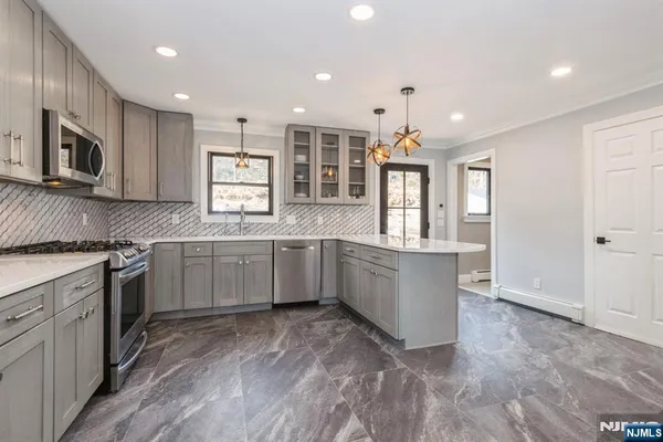 a large kitchen with stainless steel appliances granite countertop a large stove top oven a sink dishwasher and microwave oven with large wooden cabinets