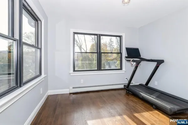 a view of a room with gym equipment on wooden floor