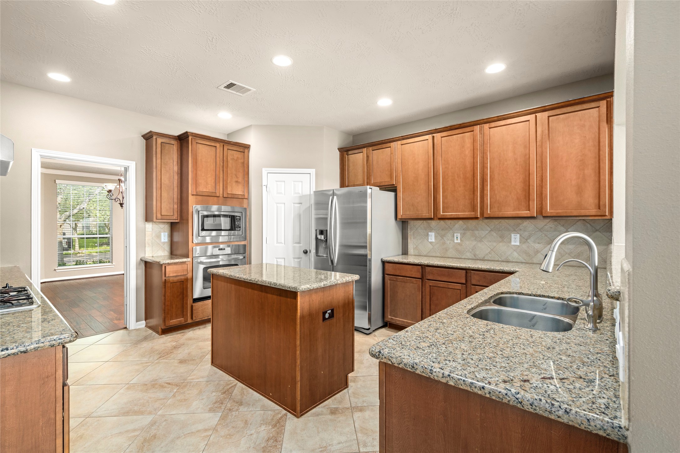 5307 Amber Sky Lane Rosharon, TX 77583 - Photo 18 of 50 The chef's kitchen impresseswith granite countertops, a generous island wired for convenience, gas cooktop, built-in microwave, and a refrigerator that stays, culinary luxury at its finest.