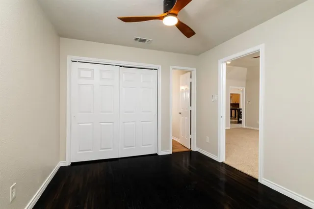 an empty room with wooden floor closet and windows