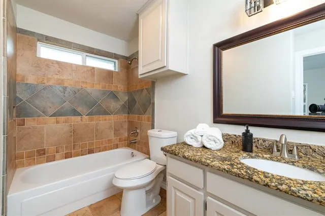 a bathroom with a granite countertop sink mirror vanity and toilet