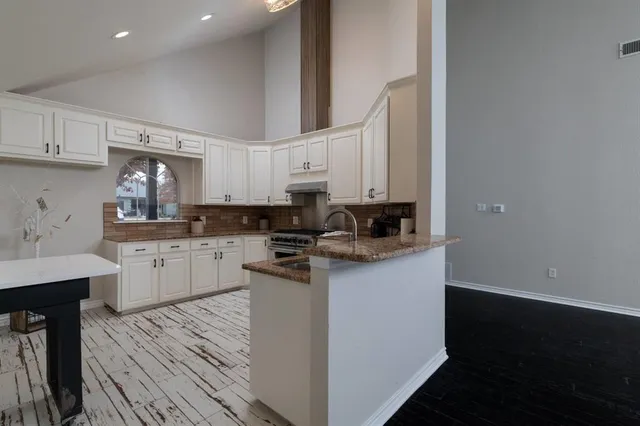 a kitchen with granite countertop a sink cabinets and stainless steel appliances