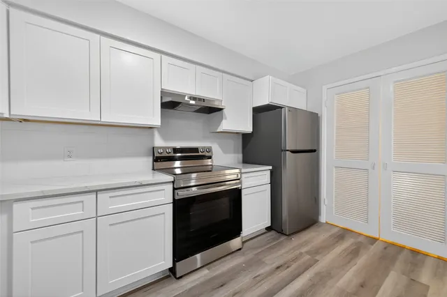 a kitchen with stainless steel appliances white cabinets and a refrigerator