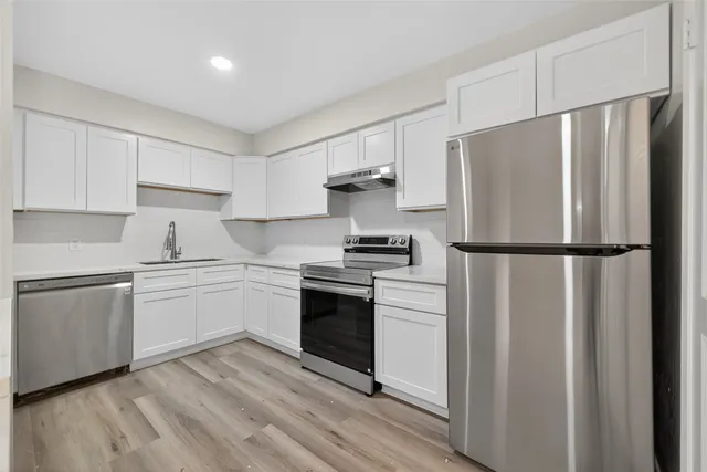 a kitchen with a refrigerator stove and white cabinets
