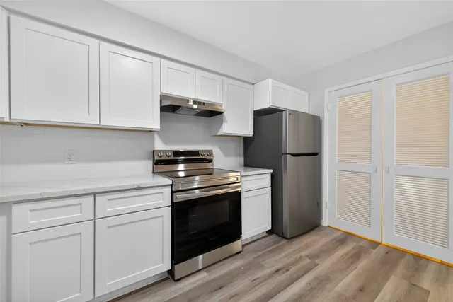 a kitchen with stainless steel appliances granite countertop a refrigerator stove and white cabinets