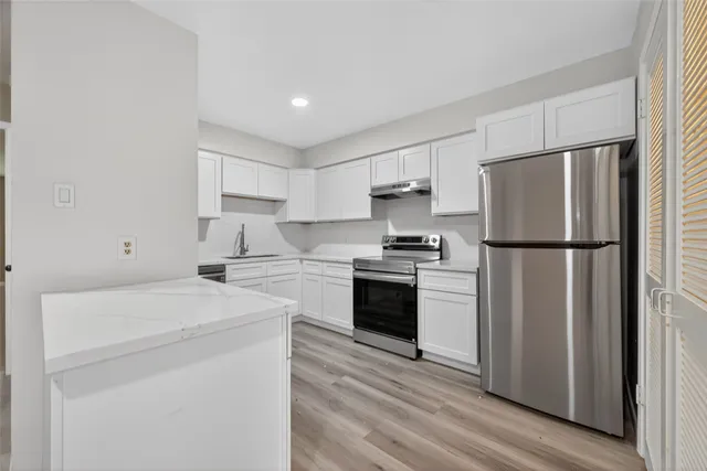 a kitchen with a refrigerator sink and white cabinets